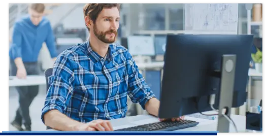 Ein Mitarbeiter sitzt an seinem modernen Arbeitsplatz, der mit einem Computer, Tastatur und Maus ausgestatet ist.