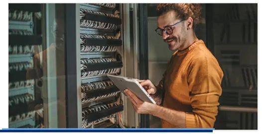 Ein IT-Techniker steht vor einem Server und führt eine Wartung durch.