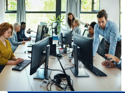 Eine Gruppe von Mitarbeitern arbeiten in Ihrem Großraum Büro und bedienen Computer, Maus und Tastatur.