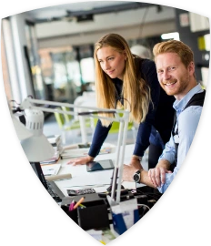Zwei Mitarbeiter sitzen an einem Schreibtisch und arbeiten an einem Computer.