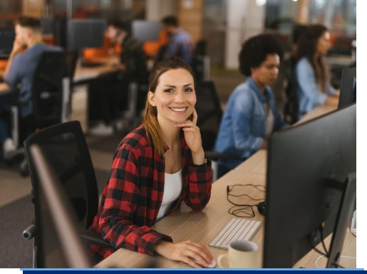 Eine junge Mitarbeiterin sitzt an Ihrem Schreibtisch und arbeitet an Ihrem Computer.