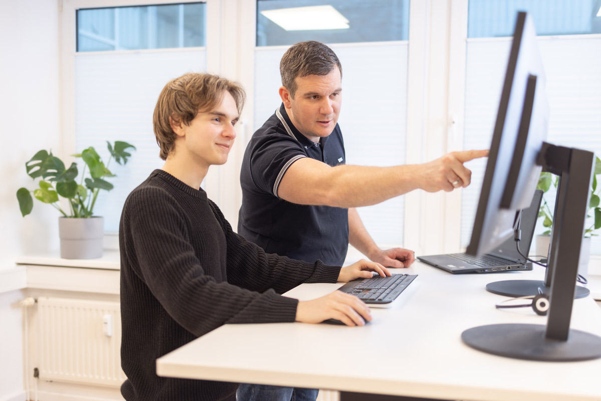 Zwei IT-Guard-Mitarbeiter besprechen gemeinsam eine Aufgabe am Bildschirm.